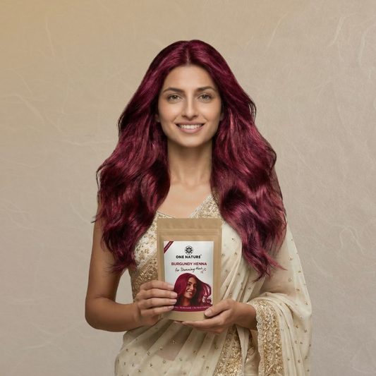 Woman with burgundy hair holding a product package against a beige background