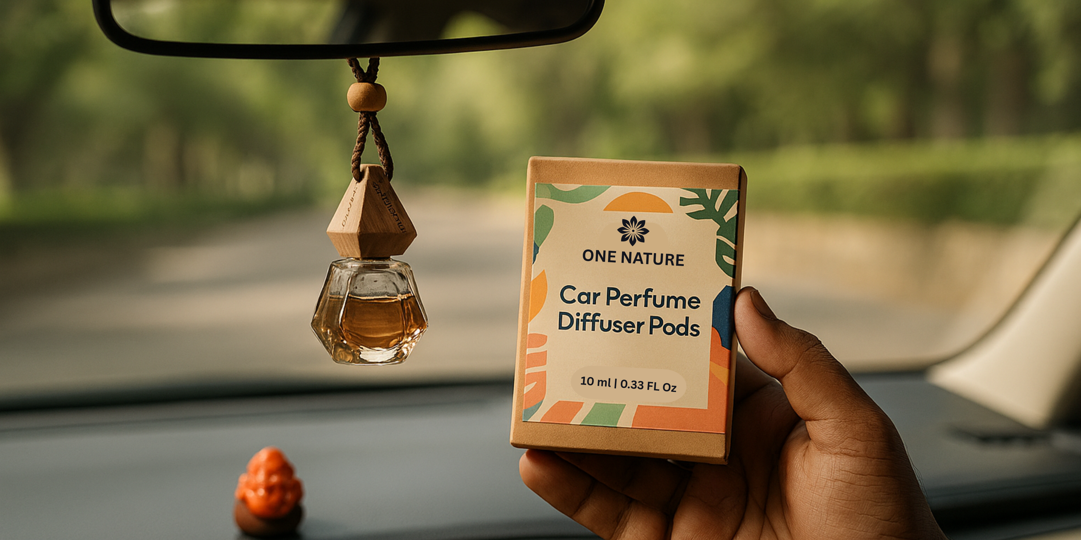 Car perfume diffuser pods held by a hand with a car's interior and rearview mirror in the background.