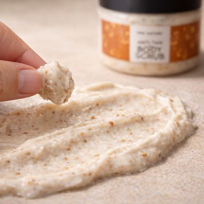 Hand holding a scoop of creamy texture with a jar in the background