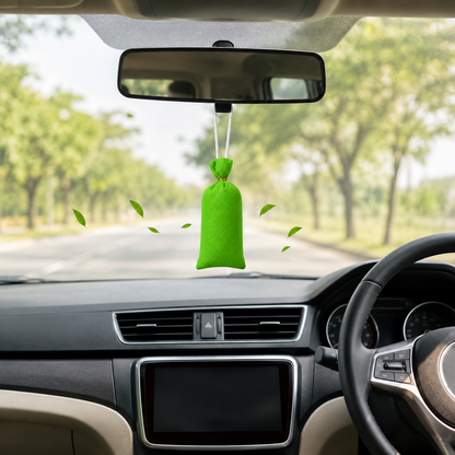 A bright green car air freshener hanging ornament suspended from the rearview mirror inside a car, with a blurred road and trees visible through the windshield.