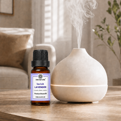 A bottle of One Nature Lavender Premium Aroma Oil stands next to a ceramic diffuser on a wooden table, with steam visibly rising from the diffuser in a softly lit home interior.