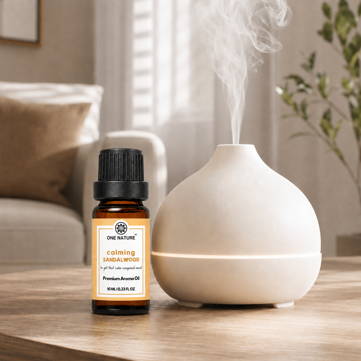 A small amber bottle of One Nature Calming Sandalwood essential oil stands next to a white ceramic diffuser on a wooden table, with steam rising from the diffuser in a softly lit living room setting.